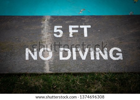 Words on concrete warn swimmers that the depth of the swimming pool is only 5 feet and that diving is prohibited in the interest of safety.