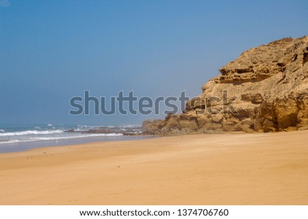 detail of a rocky and sandy beach outside of oualidia, morocco, on a bright sunny day with some mist