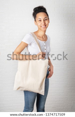 Young african woman holding white eco bag
