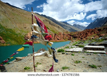 here is the picture of flags and a beautiful green lake looking awesome and also covered with mountains and blue sky