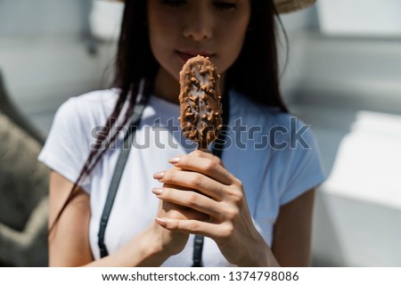 Attractive Asian Tourism holding Ice cream covered with chocolate and almonds sticks.