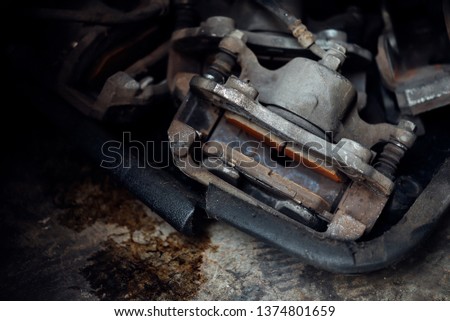 Car mechanic or serviceman checking a disc brake and asbestos brake pads it's a part of car use for stop the car for safety at front wheel this a used old part for change at car garage