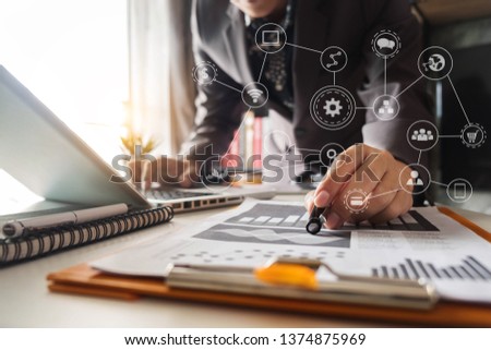 businessman or Designer using tablet with laptop and document on desk in modern office with virtual interface graphic icon data diagram.