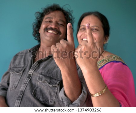 A happy indian couple shows ink-marked fingers after casting vote in Election. Selective focus.