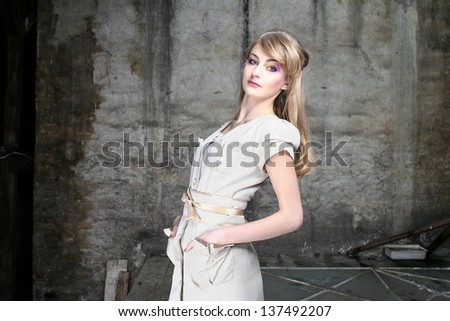 Beautiful young blonde in grey grunge studio, safari style