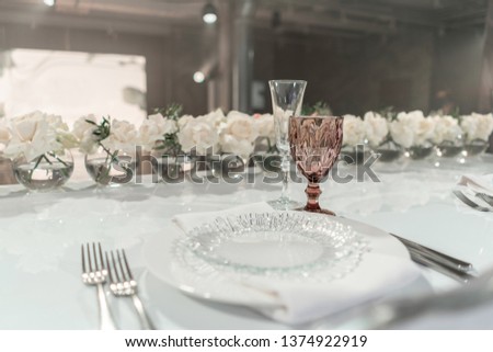 The table of the newlyweds. Small flower arrangements in ball glass vases. Interior of restaurant for wedding dinner, ready for guests. Catering concept.