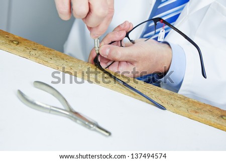 Optician fixing hinge of glasses with a screwdriver Royalty-Free Stock Photo #137494574