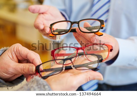 Optician offering a customer a choice of different glasses Royalty-Free Stock Photo #137494664