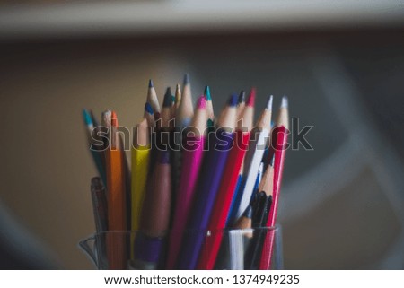 Rainbow colored coloring pencils in glass measuring beaker with rocky backdrop background