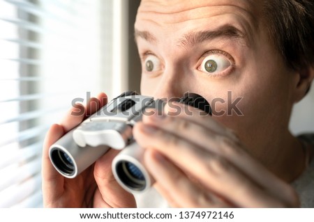 Surprised man with binoculars. Curious guy with big eyes. Nosy neighbour stalking or snooping secrets, gossip and rumour. Silly funny face. Shocked about unbelievable news. Stalker peeping people. Royalty-Free Stock Photo #1374972146