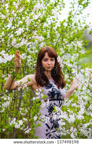 brunette girl standing on nature around blooming cherry tree with white flowers