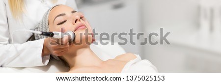 Beautiful young woman getting rejuvenating and tightening skin treatment at professional cosmetic salon. Royalty-Free Stock Photo #1375025153