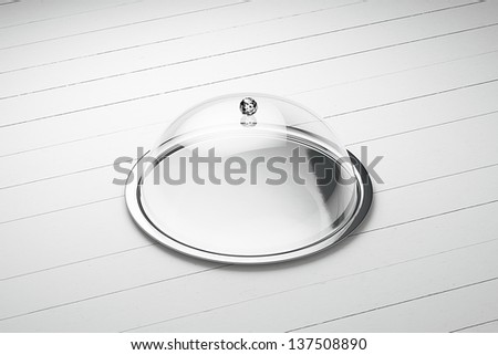 silver tray with glass cover on a white wooden background