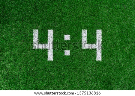 Football score 4:4.White numbers four and four are drawn on the green grass,creative scoreboard