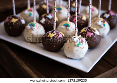 Cake pops on white plate on top of wooden box