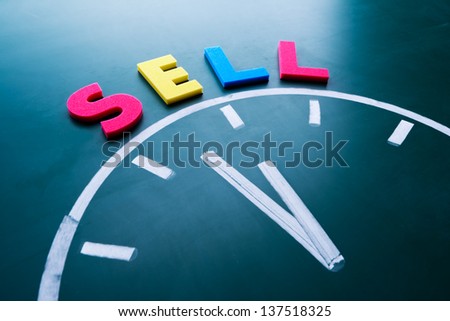 Time to sell concept, color word and clock on blackboard