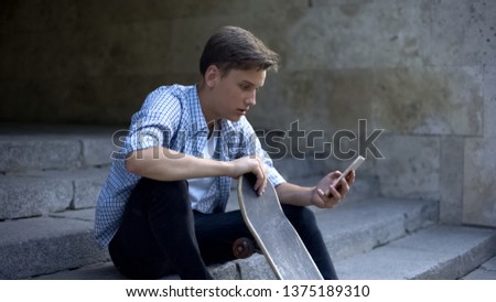 Skater boy sitting on steps and scrolling smartphone, ordering sport equipment
