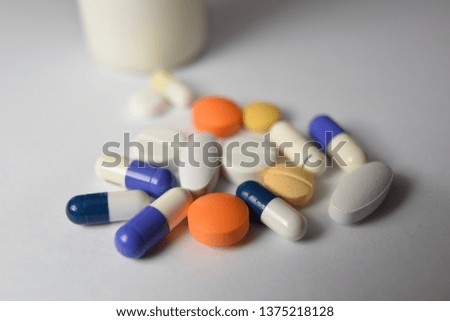 Various medical pills and capsules are split on a white background.