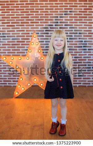 Portrait of a little girl in the studio in full growth against the background of a brick wall. Superstar