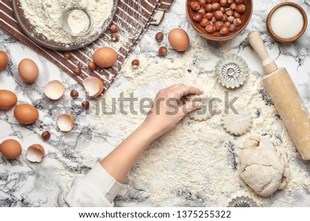 Close-up shot. Top view of a baker cook place, hands are working with a raw dough on the marble table background.