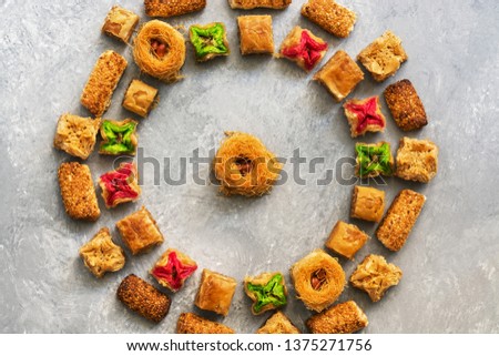 Middle Eastern traditional dessert baklava on a gray background. Round frame of arabic sweets. Overhead view.