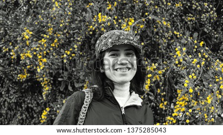 Young beautiful woman smiling on yellow flowers and green tree background. Black and white photography. Meadow, tranquility and pasture concept.