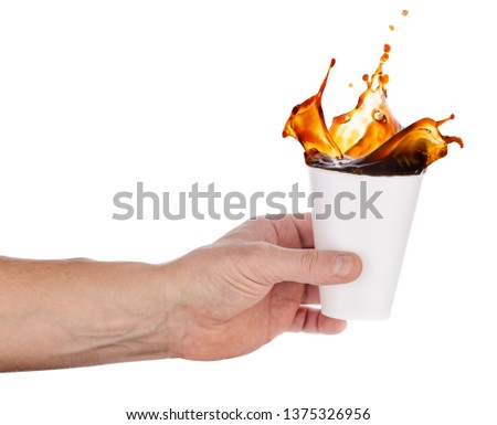 White disposable glass with a splash of coffee in an outstretched hand. Isolated on white background. Preparation for the design project