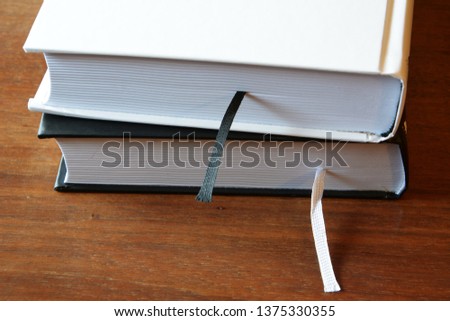 Two books - white and black - lie on a dark wooden table