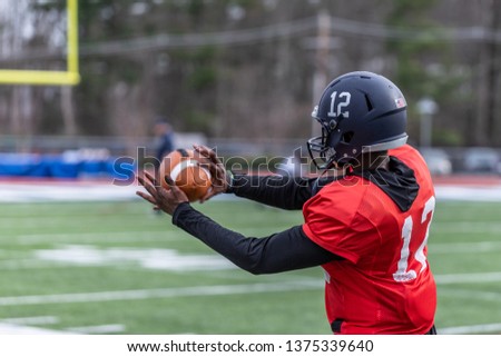 An African American football player is catching a ball