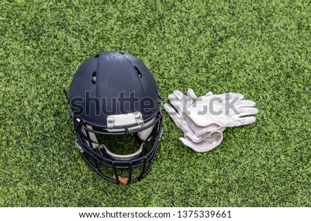 Arerial view of a football helmet and a pair of white gloves are laying on the grass