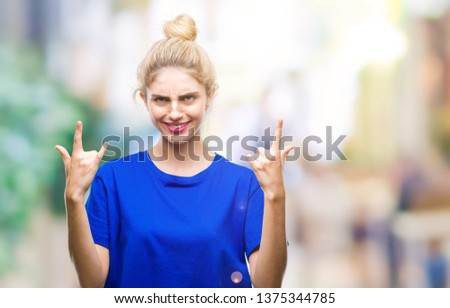 Young beautiful blonde and blue eyes woman wearing blue t-shirt over isolated background shouting with crazy expression doing rock symbol with hands up. Music star. Heavy concept.