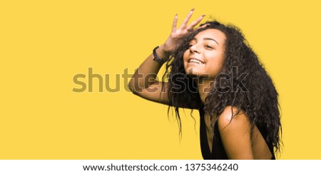 Young beautiful girl with curly hair wearing fashion skirt very happy and smiling looking far away with hand over head. Searching concept.