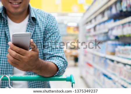 Close up of a man using smartphone and shopping in a supermarket , shopping concept