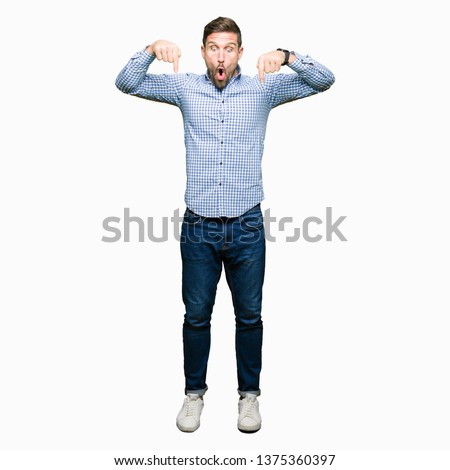 Handsome business man with blue eyes Pointing down with fingers showing advertisement, surprised face and open mouth