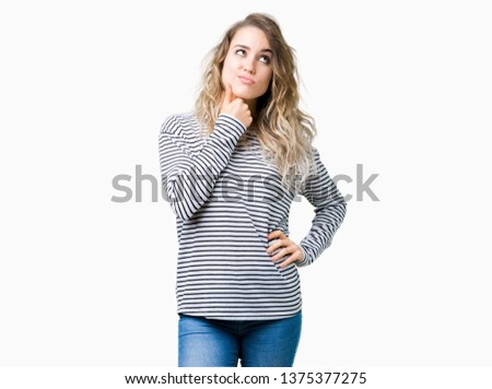 Beautiful young blonde woman wearing stripes sweater over isolated background with hand on chin thinking about question, pensive expression. Smiling with thoughtful face. Doubt concept.