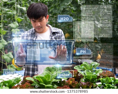 young smart Asia Farmer using Ar,Vr,3d projection glass Technology at his smart farm.