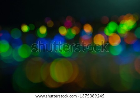 Blurred multicolor bokeh circles on dark background. Defocused lens flare glow. Abstract design.