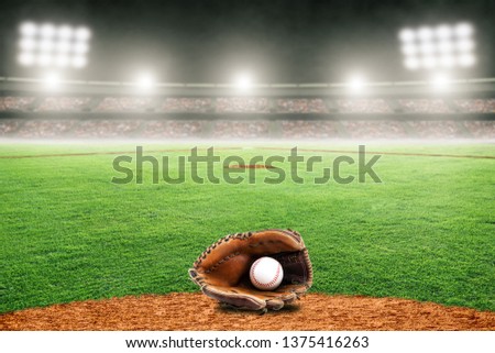 Baseball glove on field at brightly lit outdoor stadium. Focus on foreground and shallow depth of field on background and copy space.