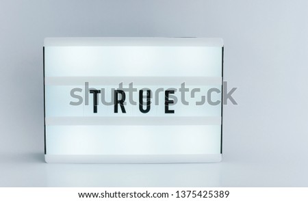 Photo of a light box with text, TRUE, over white isolated wall 