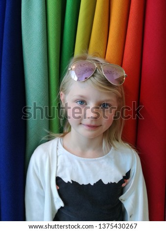 Beautiful pretty little blond cool girl in a office with color Textil in background homework computer work future child