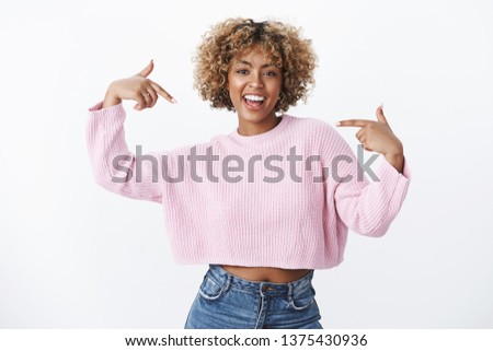 Hey it me who you need. Portrait of happy and enthusiastic good-looking dark-skinned girl with piercing and blond afro hair smiling joyfully suggesting her help pointing at herself joyfully Royalty-Free Stock Photo #1375430936