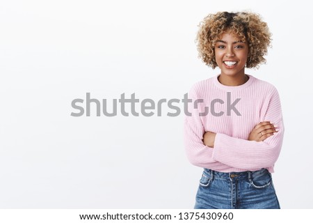 Cute african-american girl entertained with funny conversation standing relaxed and carefree with hands crossed over body smiling friendly at camera as talking, wearing warm purple trendy sweater