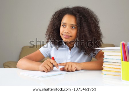 black school girl writes in a notebook, doing homework