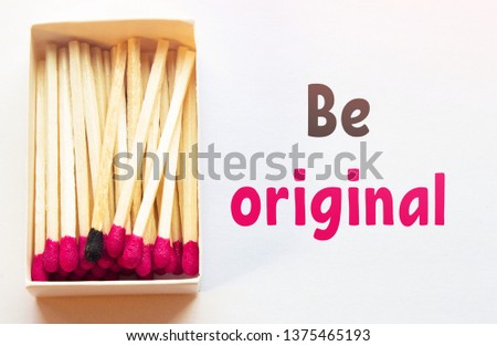 Crimson matches and one match of black color in a box. Difference, self respect and acceptance concept. Motivational phrase on the image. Opposition, unique features and individualism concept.