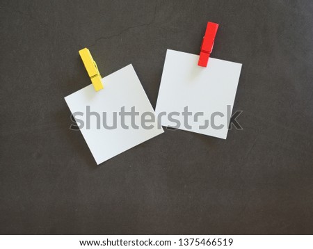 White note paper with colorful clamps on black cement floor