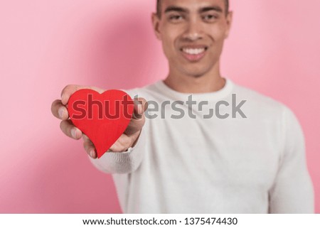 Man holding a heart-object in his straight hand. Focus to a heart,blurring background.- Image