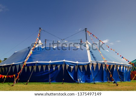 Blue circus tent in a park with colorful pennants under the light of morning