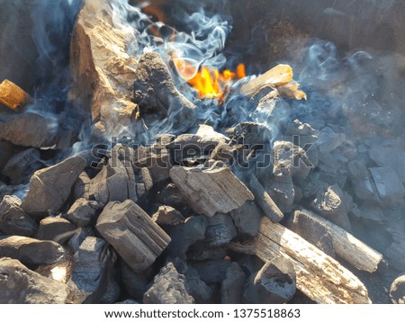 Smoke of the coal on the embers. Preparation of fire for barbecue embers. Outdoor recreation. Flames seen in the image.