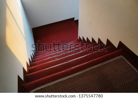 Stairs inside the building was made by the skin red carpet. The condition of the carpet is old and torn.