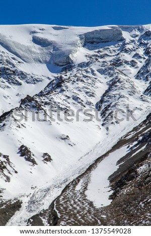 Vertical photo of snow glacier on peak of the mountain in blue sky
